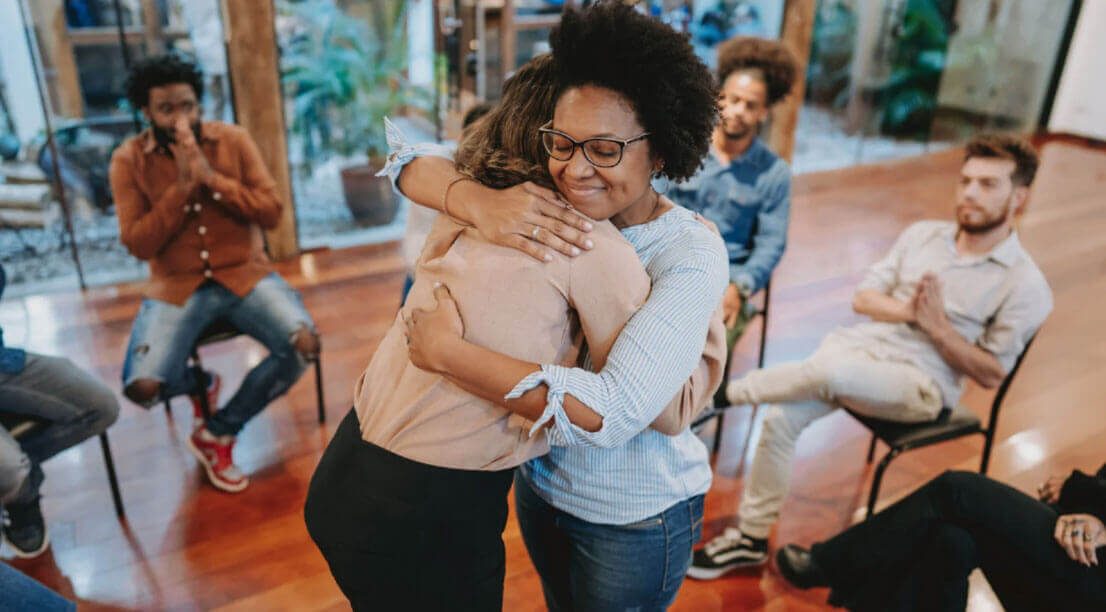 Two people hugging during a group session, showing emotional support and encouragement.
