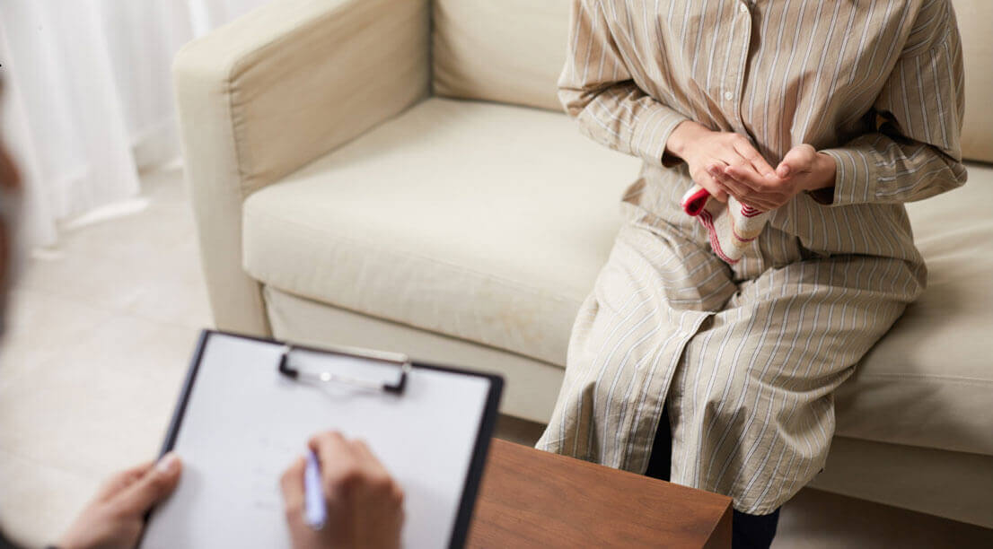 A person sitting with a counselor, holding a small item while discussing personal challenges in therapy.