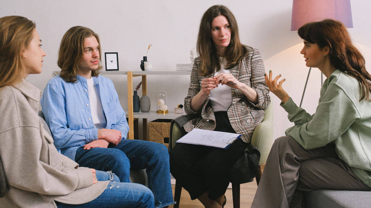 A counselor facilitates a small group discussion focused on recovery and support.