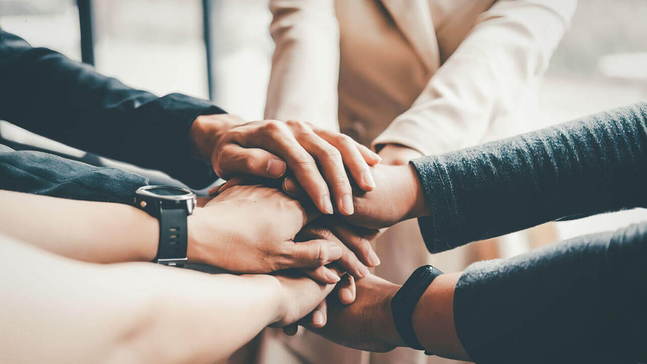 Close up of several hands stacked together in a show of unity and support.